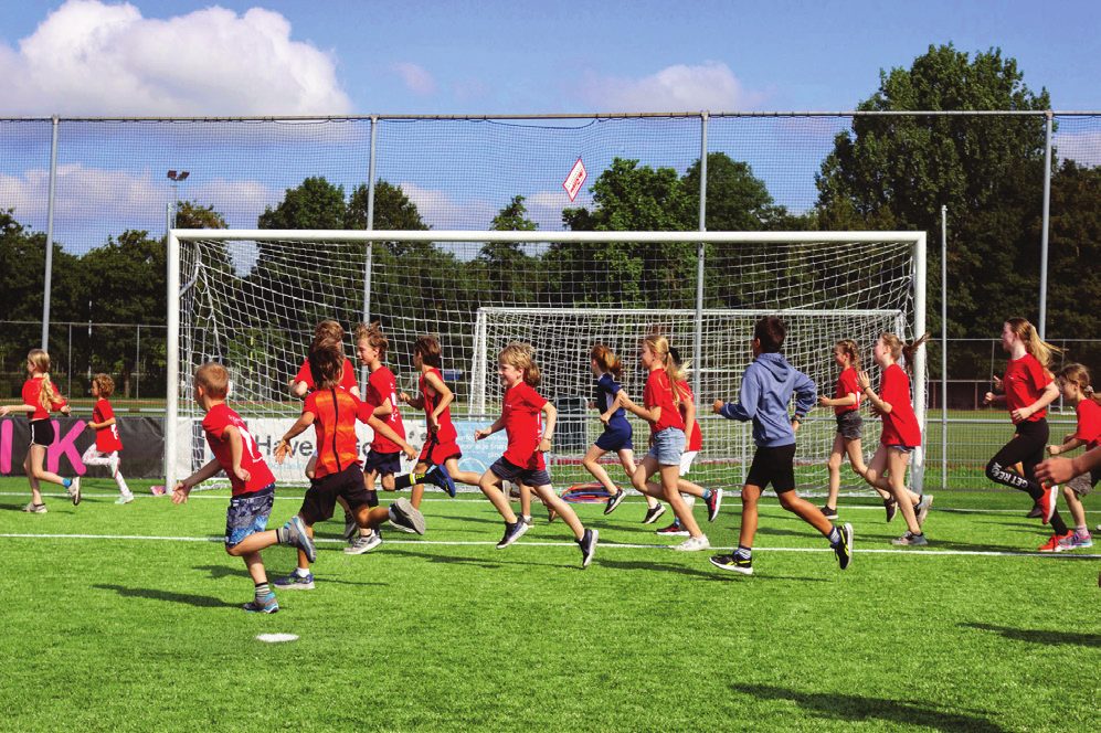 Een groep kinderen rent samen over het voetbalveld